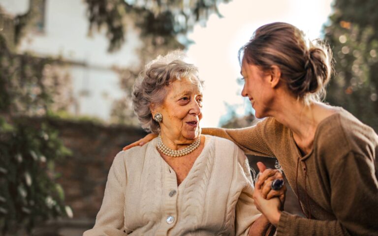 joyful adult daughter greeting happy surprised senior mother in garden